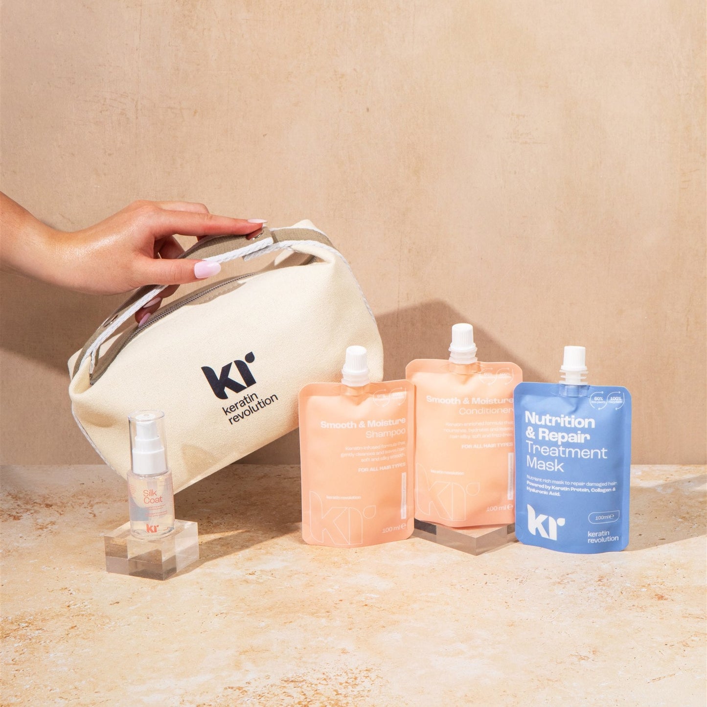 KR skincare products including a bag, bottles, and packets on a beige surface.
