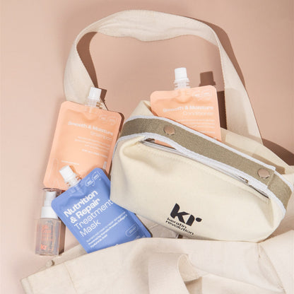 Beige tote bag with hair care products including a blue bottle and orange pouches on a beige background