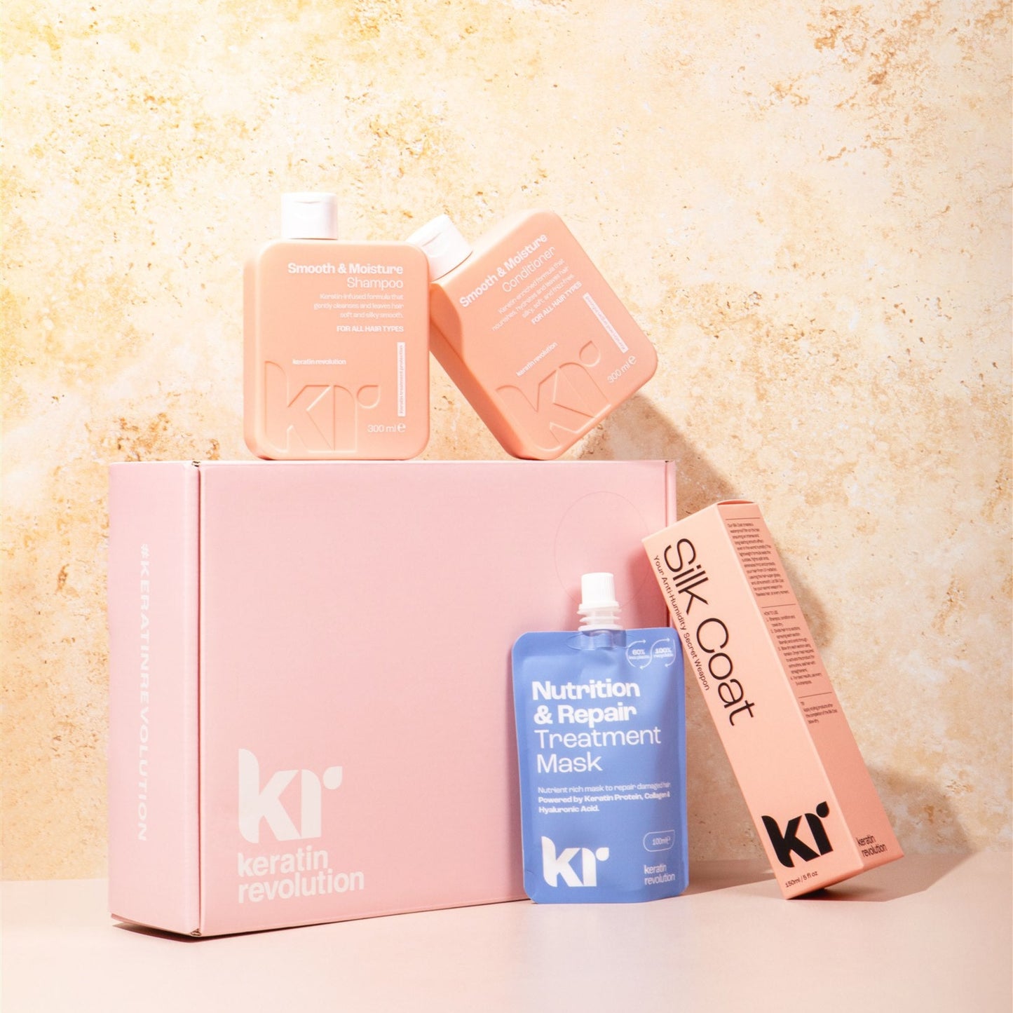 Keratin Revolution hair care products including a box, bottles, and a comb on a textured beige background.