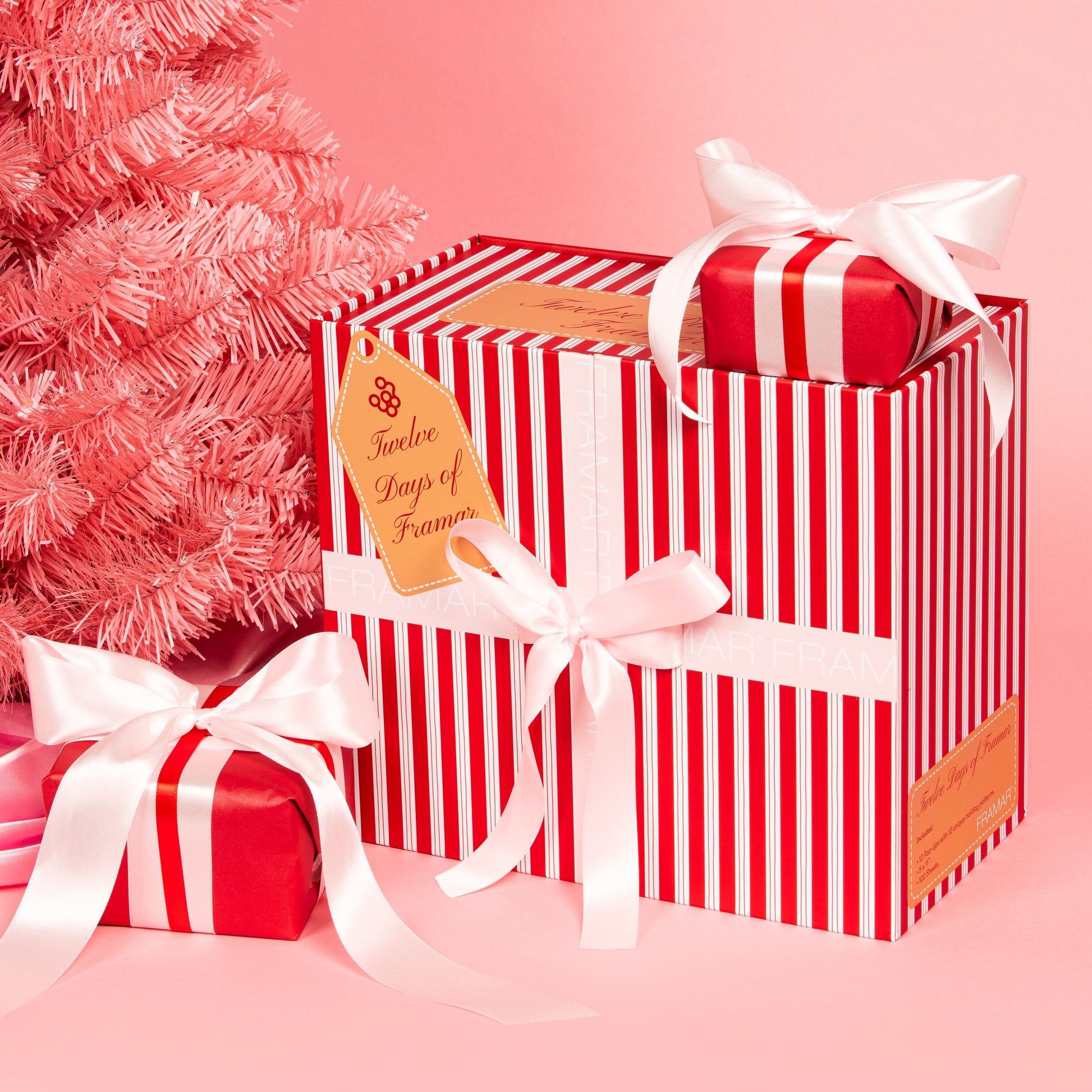 Red and white striped gift box with a bow on a pink background