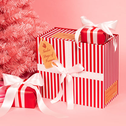 Red and white striped gift box with a bow on a pink background