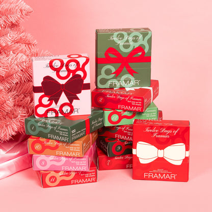 Stack of Framar product boxes with decorative bows on a pink background