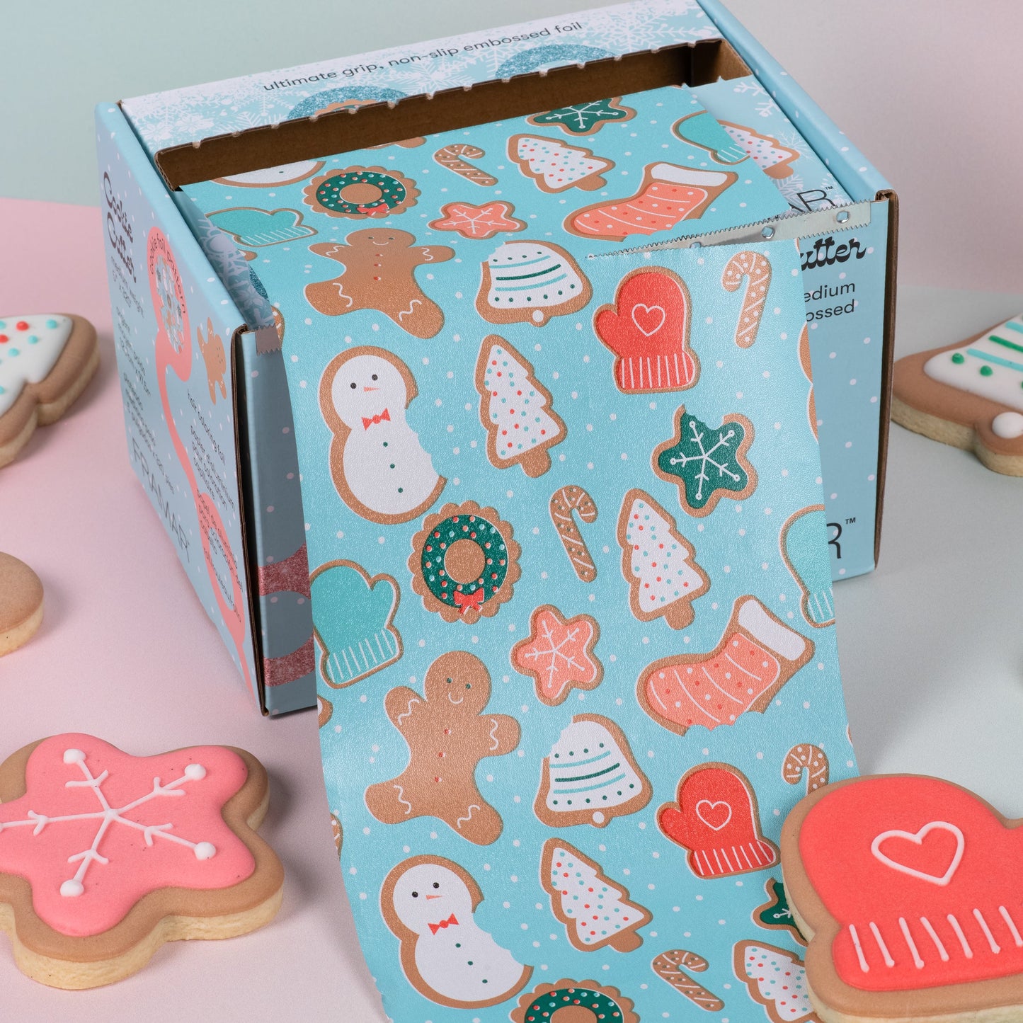 Decorative box with Christmas-themed cookies on a pink surface