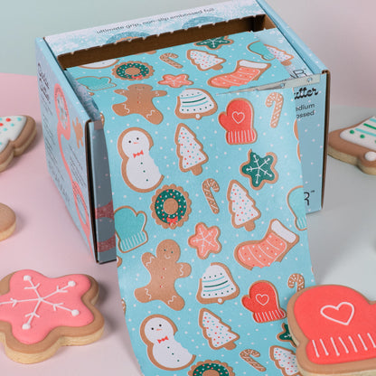 Decorative box with Christmas-themed cookies on a pink surface