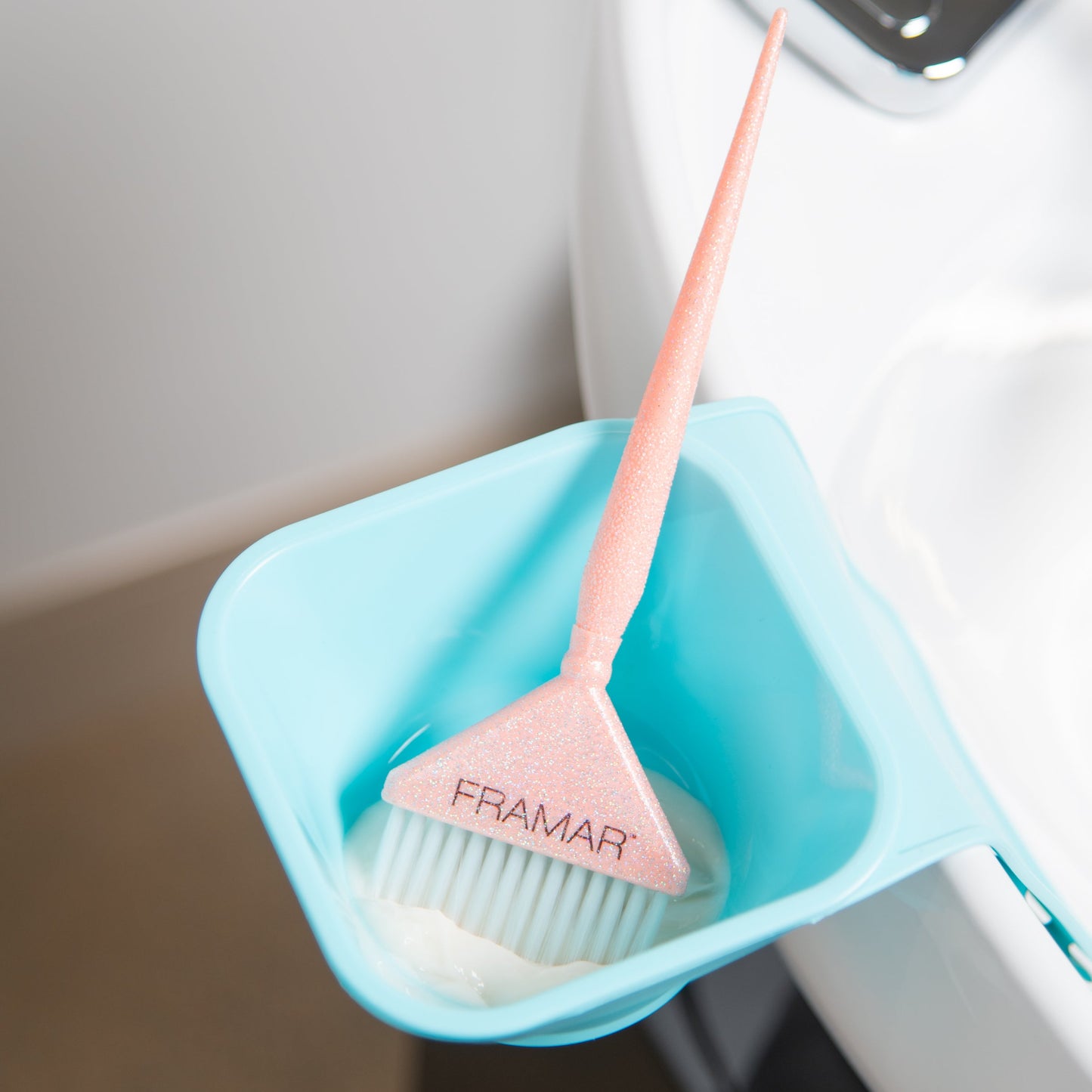 Pink cleaning brush with a blue holder attached to a sink