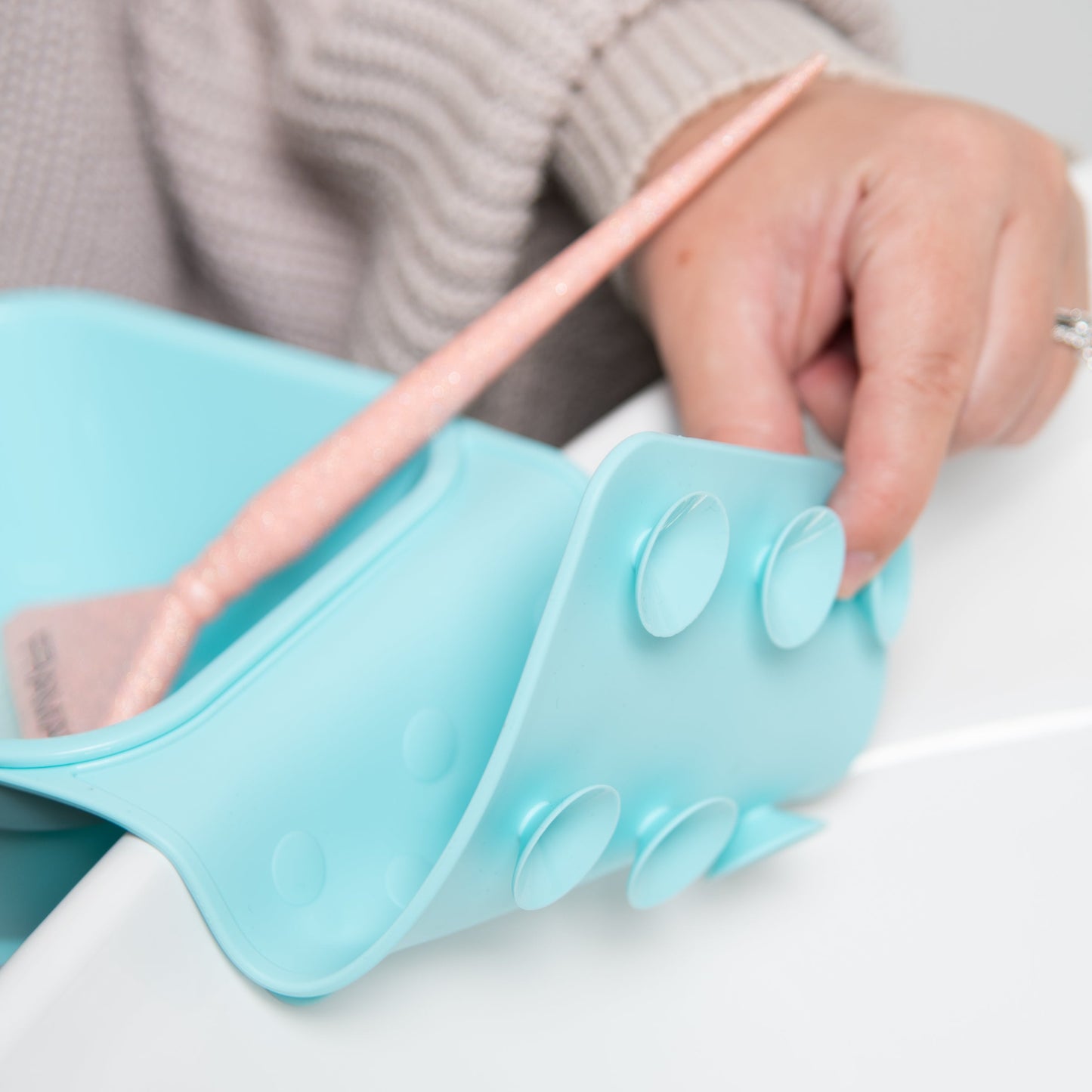 Light blue silicone shoe insert being adjusted by a person with a neutral background