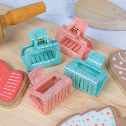 Colorful hair clips on a wooden surface with decorative cookies.